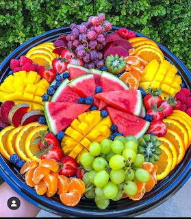 Overhead view of circular fruit platter with watermelon, citrus, grapes, and berries in colorful radial arrangement