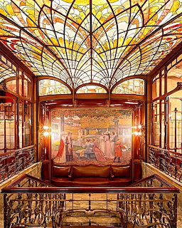 Art Nouveau interior with stained glass ceiling, mural, and ornate railings in a Brussels hotel
