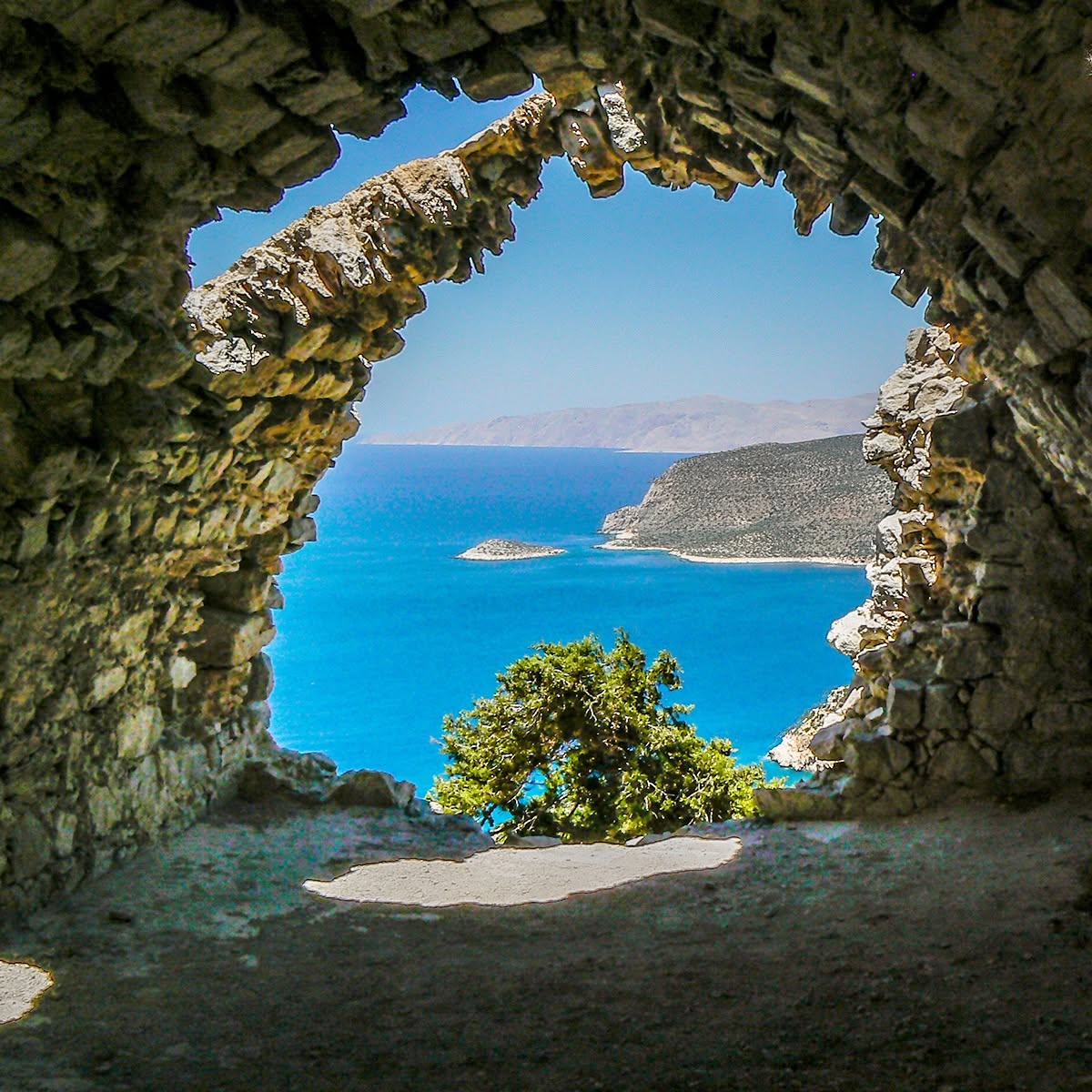 Blue sea and rocky coast seen through a stone arch opening