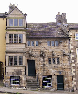 Old medieval stone house with multiple windows and entrance door, showing aged weathered facade