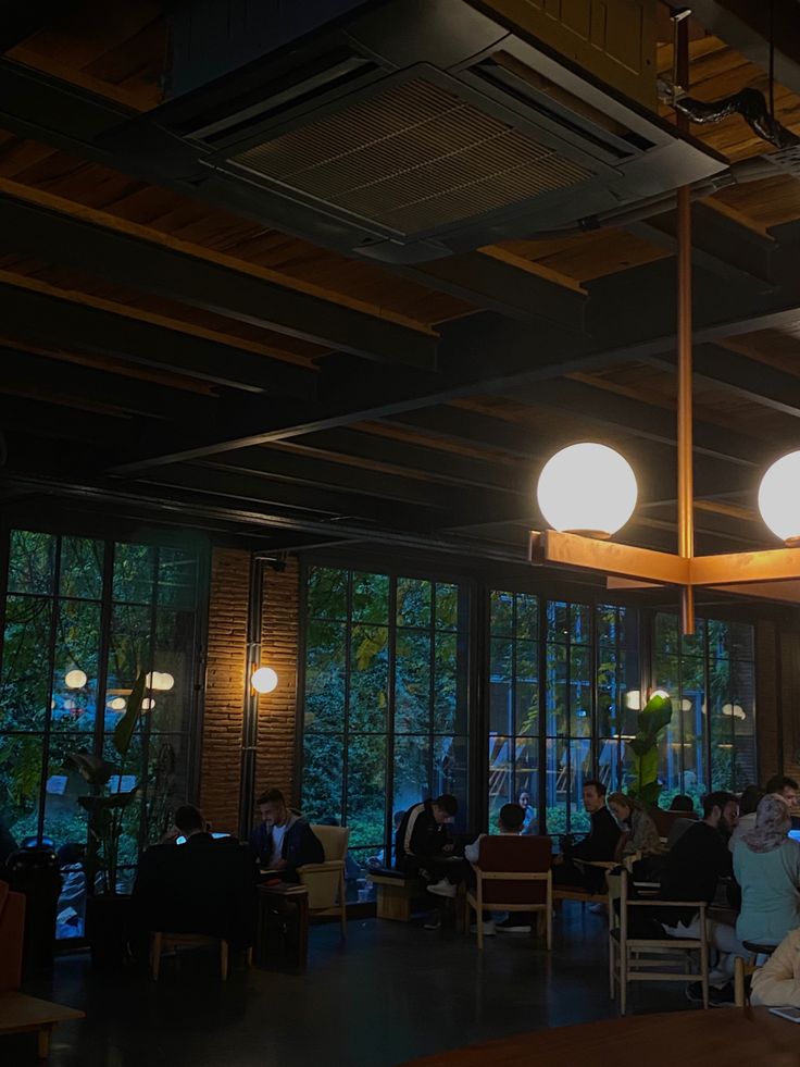 Cozy coffee shop interior with hanging lights, wooden ceiling beams, and window view of trees