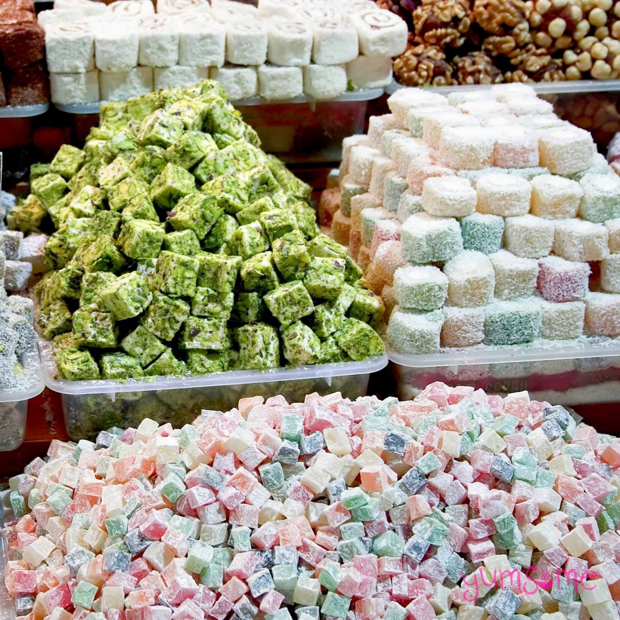 Trays of colorful Turkish delight candy including green, white, and pastel varieties displayed at a confectionery shop