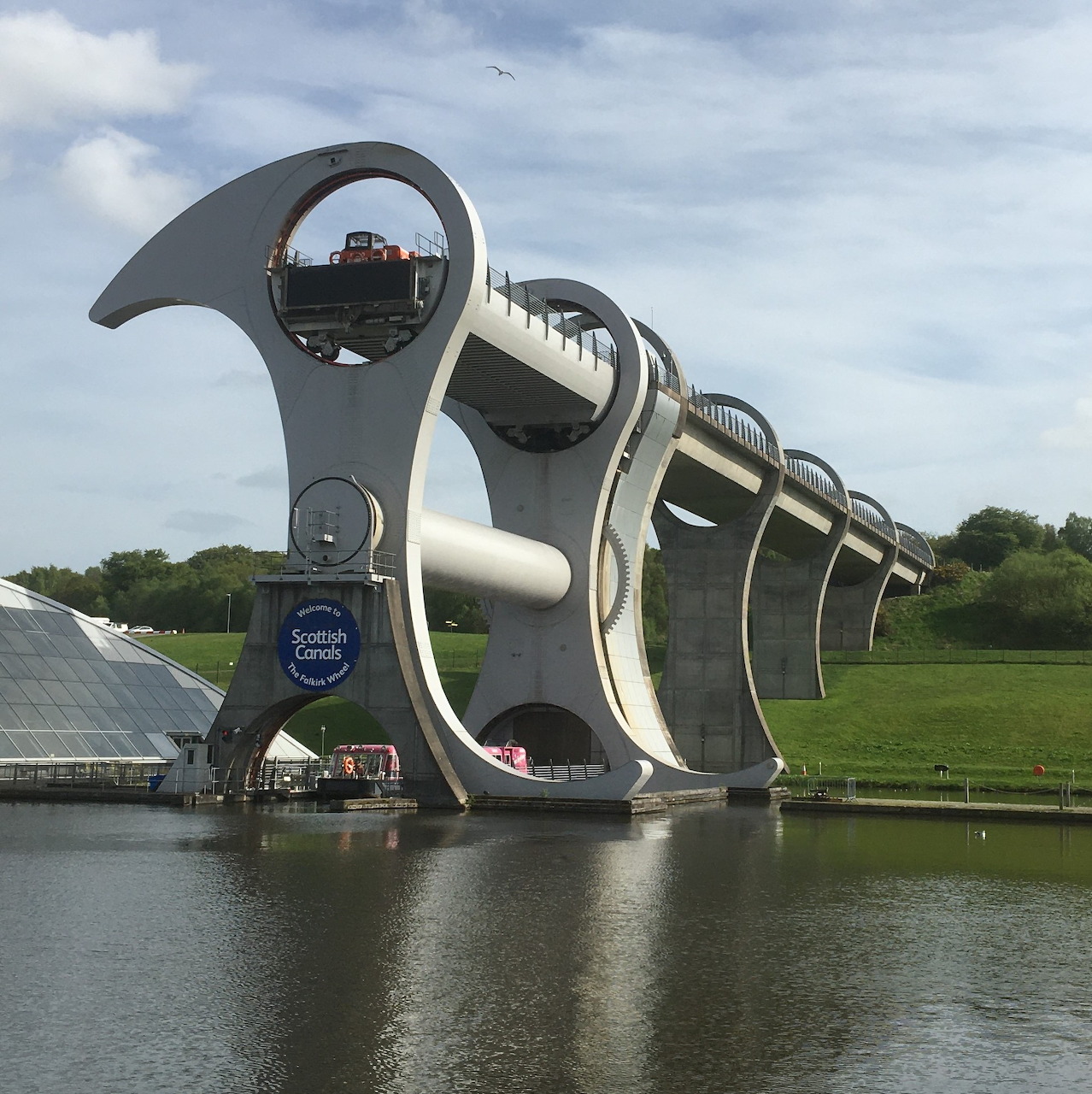 The Falkirk Wheel boat lift beside calm water under a cloudy sky