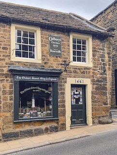 Traditional stone sweet shop with large display window and black door on a village street