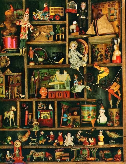 Wooden shelves crowded with antique toys including dolls, rocking horses, tin cars, and wooden figurines
