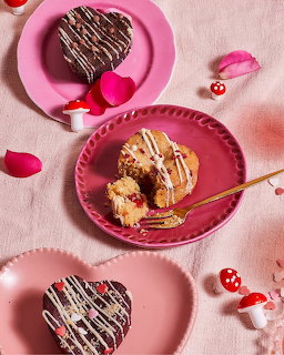 Heart-shaped chocolate desserts with white drizzle on pink plates with rose petals