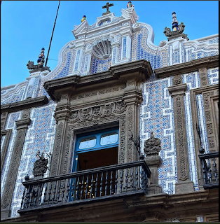 Ornate building facade with blue azulejo tiles, carved stone balcony, and baroque architectural elements