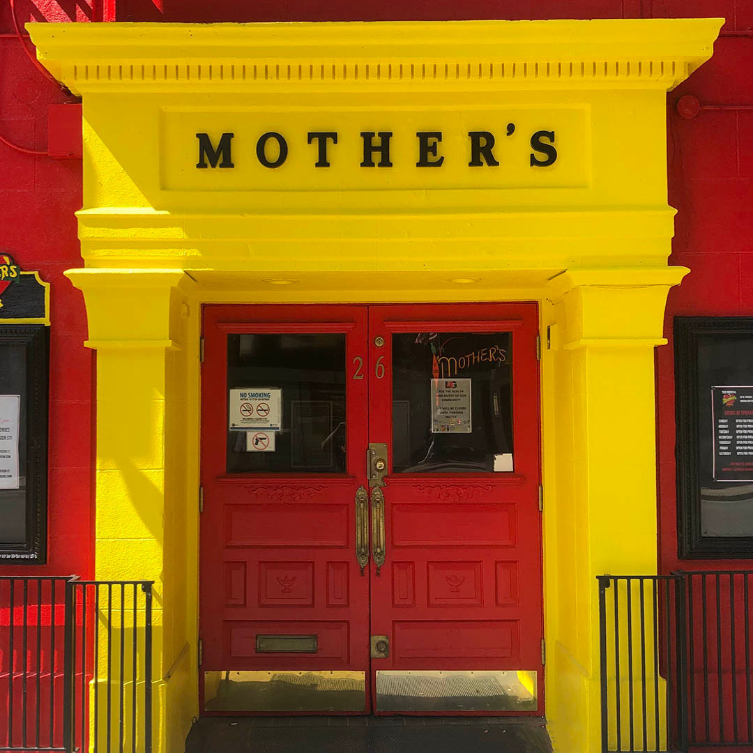 Yellow storefront entrance with a red double door and Mother's sign above