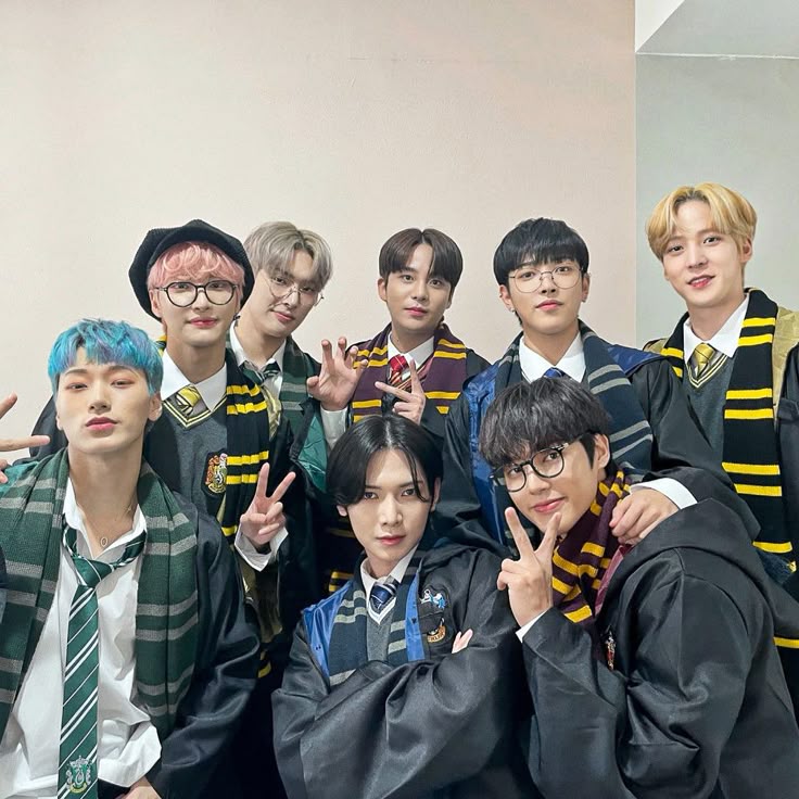 Seven young men posing indoors in wizard-style robes and striped scarves
