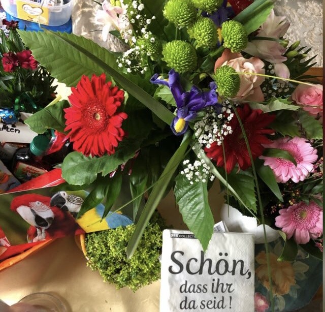 Colorful bouquet with red, purple, pink flowers and green mums with greeting card reading Schön, dass ihr da seid