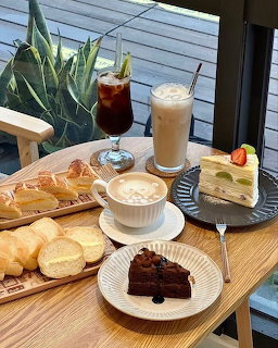 Iced and hot coffee with cake slices and bread on a wooden table
