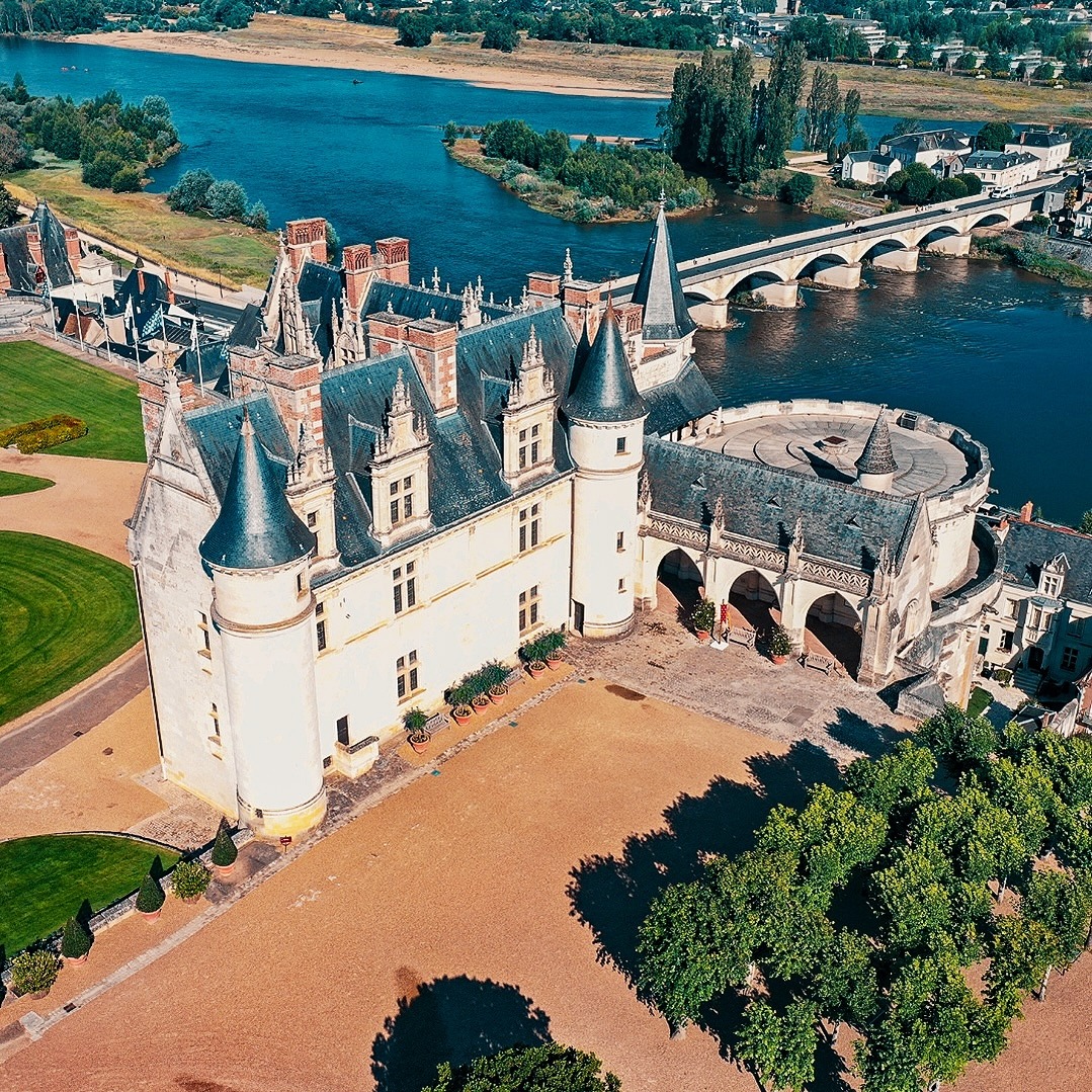 Aerial view of white medieval castle with towers beside river and bridge in Loire Valley France