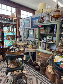 Antique shop interior filled with vintage furniture, lamps, collectibles and decorative items on shelves
