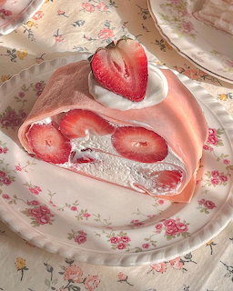 Slice of strawberry Swiss roll cake with cream and fresh strawberries on floral plate