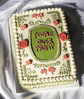 Decorated sheet cake with green frame reading People Over Profit, pink roses, and vine ping details