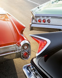 Close-up of vintage car tailfins and taillights in red, black, and mint green
