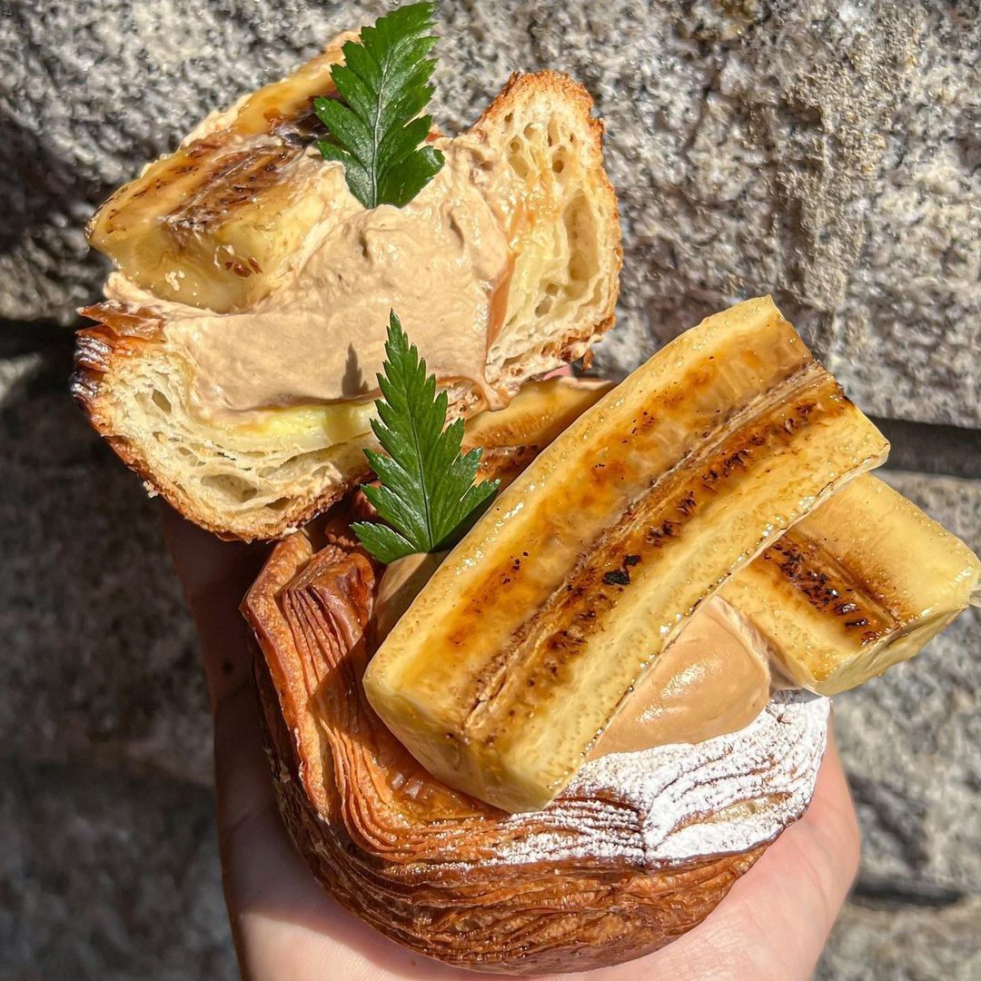 Flaky pastry with banana slices and cream held in a hand