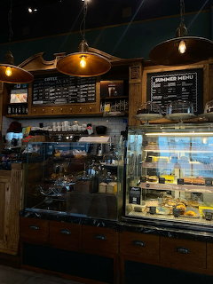 Dark cafe interior with copper pendant lamps, chalkboard menus, and a glass pastry display case