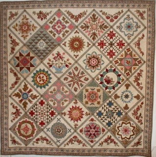 Vintage patchwork quilt with geometric and floral patterns in red, beige, and brown tones