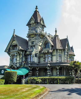 Ornate Victorian mansion with tall turret and decorative architectural details under blue sky