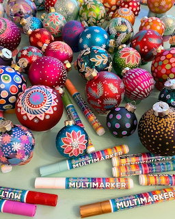 Collection of brightly painted Christmas baubles with detailed patterns and dots, arranged with art markers