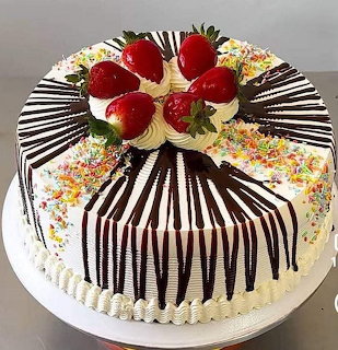 Round cake with white frosting, black chocolate drizzle stripes, strawberries and sprinkles on top
