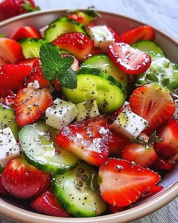 Bowl of strawberry cucumber salad with kiwi slices, mint leaves, and white cheese cubes