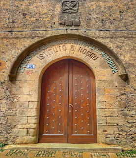 Arched wooden door in a weathered stone wall with carved lettering above