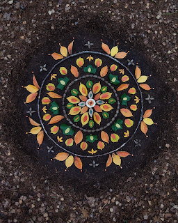 Circular mandala pattern created with colorful autumn leaves on dark textured surface