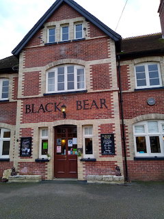 Red brick Black Bear pub building with white windows and dark roof