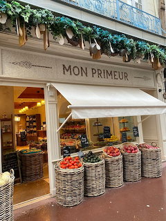 Street-side fruit and vegetable shop with baskets of produce outside under a white awning