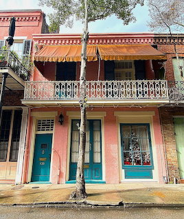 Pink historic building with ornate balconies and turquoise doors on a street corner
