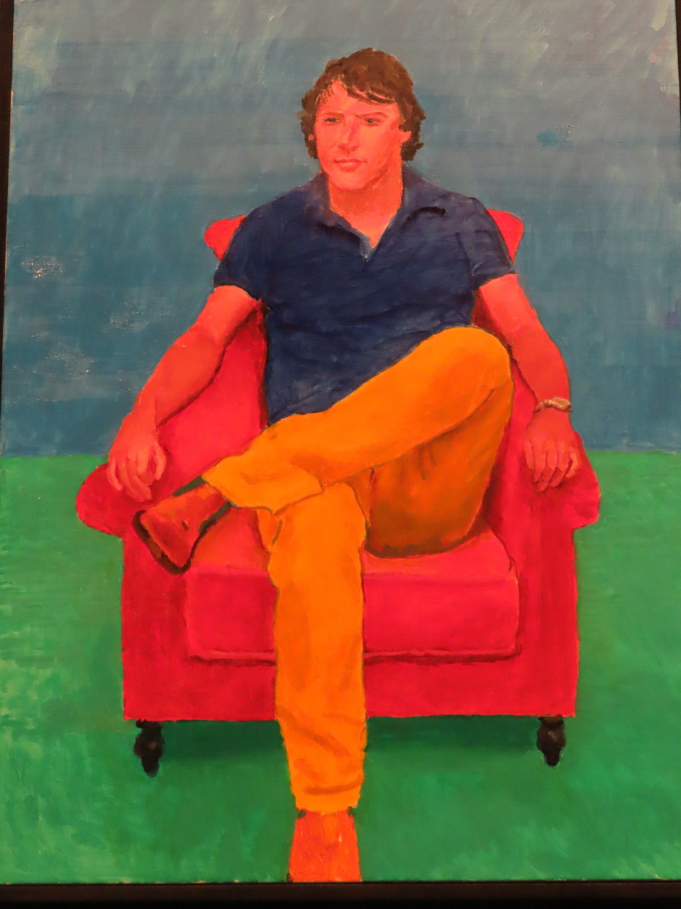 Painting of a man sitting in a red armchair wearing orange pants and a navy shirt, blue and green background