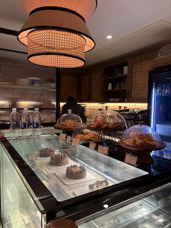 Cafe bakery display counter with pastries and cakes under glass domes and a woven pendant light