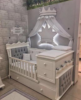 White painted wooden baby crib and changing table with fabric canopy and grey cushions in nursery room