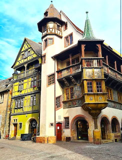 Historic half-timbered buildings with tower and yellow facade in Colmar, France