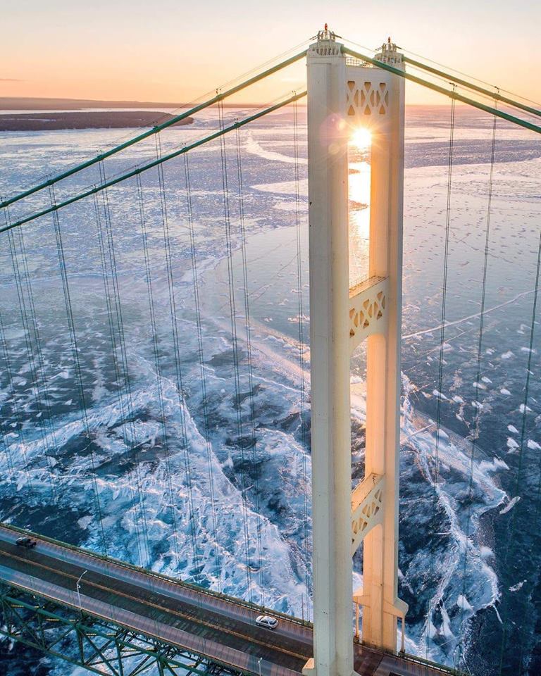 Mackinac Bridge tower over frozen lake waters at sunset