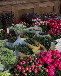 Colorful flower market with pink peonies, red roses, tulips, and green foliage in wrapped bouquets
