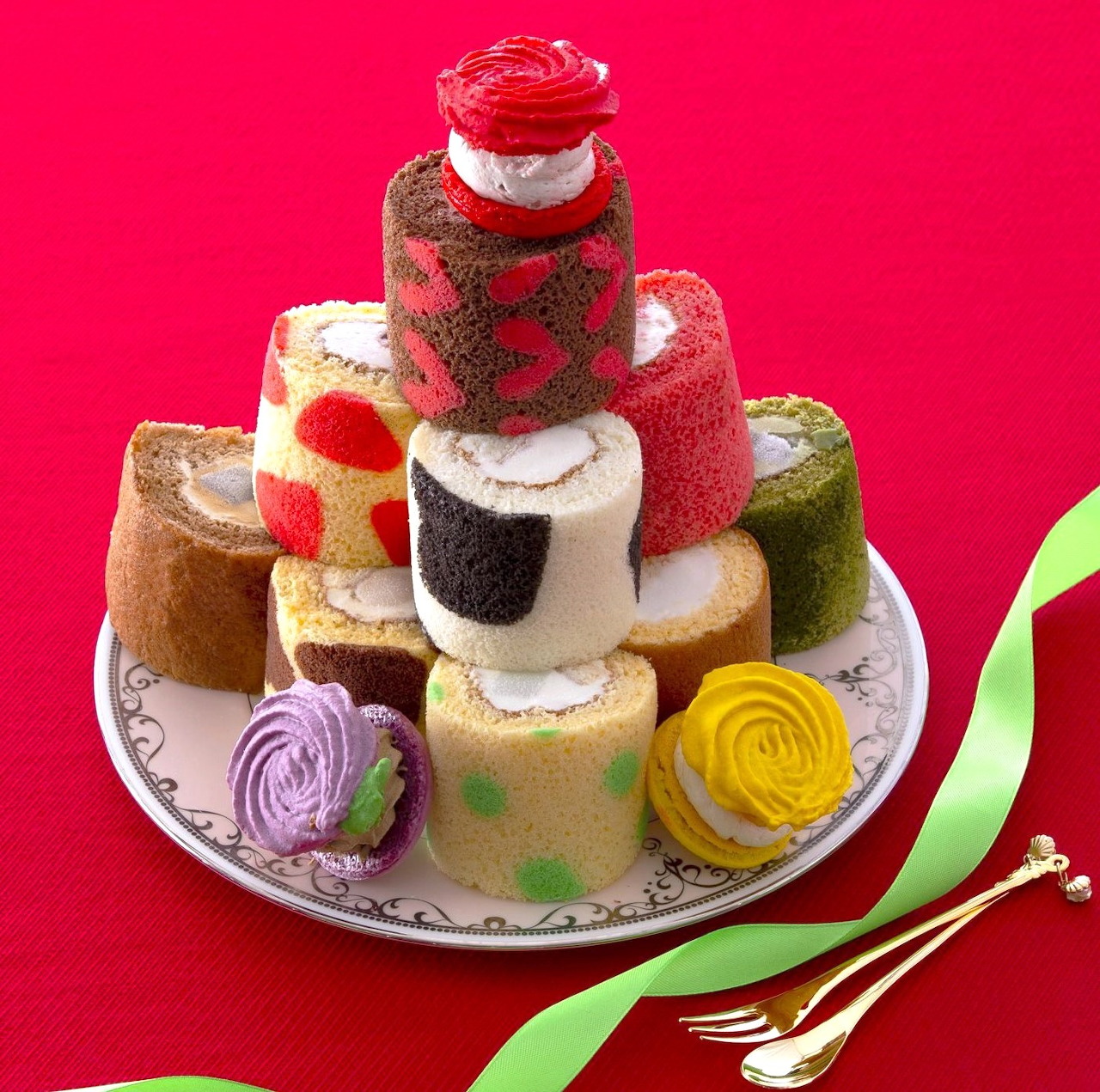 Plate of assorted colorful Swiss roll cakes on a red background