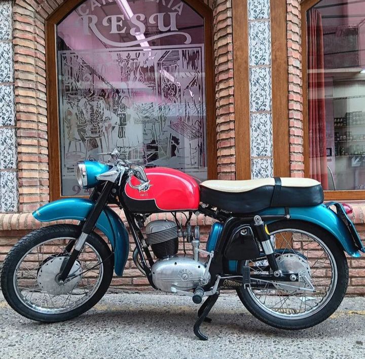 Vintage red and blue motorcycle parked beside a decorative storefront window