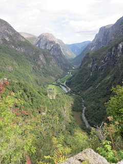 Narrow green valley in Norway with steep mountains, winding river, and dense forest