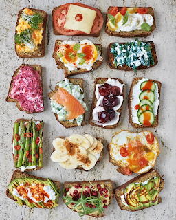 Variety of colorful open-faced sandwiches with different toppings arranged on white surface