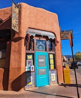 Adobe building with turquoise door and colorful tile decorations in Santa Fe, New Mexico