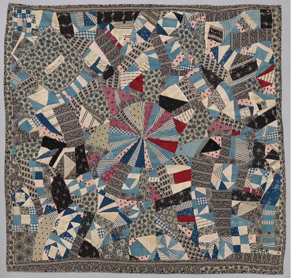 Vintage patchwork quilt with geometric fan patterns in blue, red, and cream tones