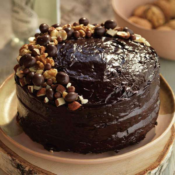 Chocolate cake with dark frosting, nuts, and chocolate candies on a plate