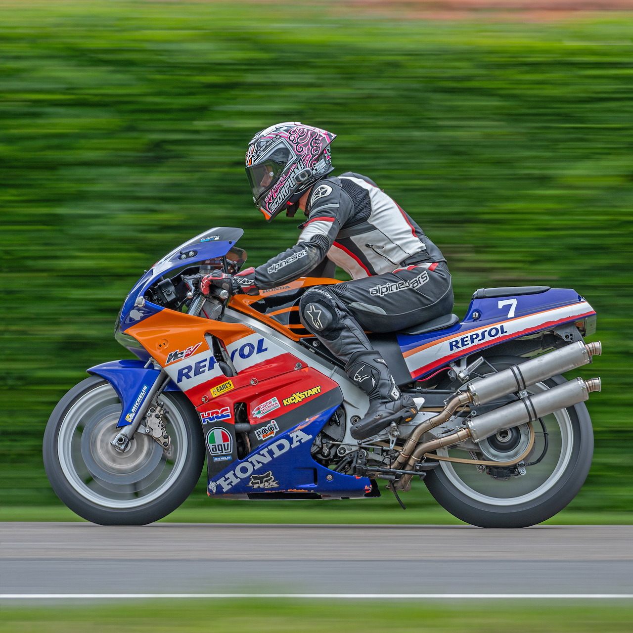 Rider on a blue and orange Repsol Honda RC30 racing motorcycle with number 7