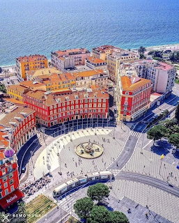 Aerial view of Place Masséna, Nice, France, with colorful buildings and the sea in the background