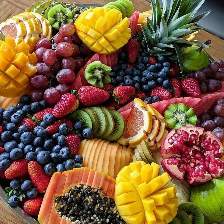 Colorful arrangement of sliced tropical fruits and berries on wooden board