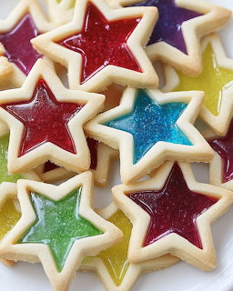 Assorted star-shaped cookies with colorful icing centers in red, blue, green, and yellow on white background