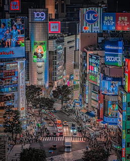 Aerial view of Shibuya crossing at night with colorful neon signs and pedestrians